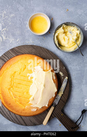 Eine Runde hausgemachte orange Kuchen teilweise mit Butter Puderzucker. Stockfoto