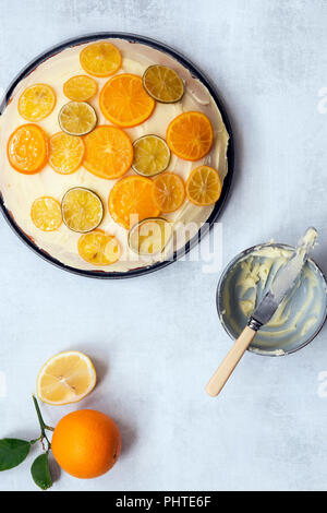 Eine Runde orange Kuchen mit Butter und Puderzucker mit Scheiben von kandierte Zitrone, Limette und orange gehalten. Stockfoto