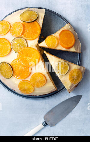 Ein großer runder hausgemachte Kuchen iced orange und dekoriert mit Scheiben von kandierten Orangen, Zitronen und Limonen. Stockfoto