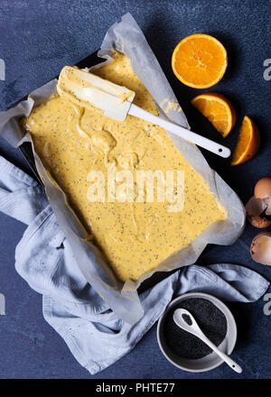 Orange Mohn kuchen Teig in Zinn mit Orangen und einer Schüssel mit Mohn. Stockfoto