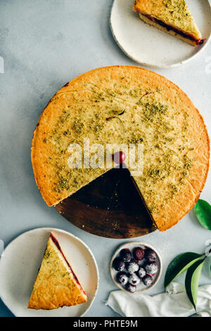 Eine Cherry Pie in Scheiben geschnitten und serviert auf zwei Platten von der Ansicht von oben fotografiert. Kirschen mit Puderzucker und grüne Blätter begleiten. Stockfoto