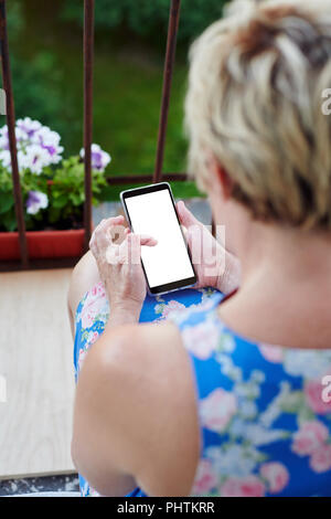 Anonyme Frau mit Smartphone auf dem Balkon Stockfoto