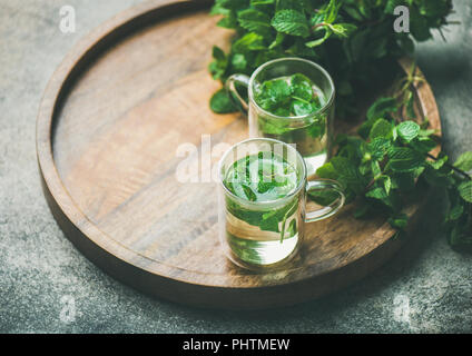 Heißen Kräutertee Pfefferminztee im Glas Becher mit Blättern Stockfoto