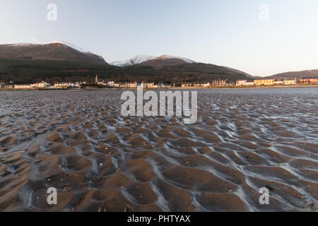 Wellen in nassem Sand mit Blick auf Newcastle und Mourne Mountains, County Down, Nordirland. Stockfoto