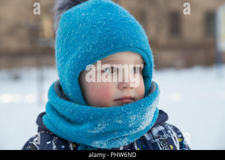 Kind Junge 2-3 Jahre im Winter draußen in Blau gestrickte Wollmütze mit pompon und Schal - snood. Close-up Portrait Stockfoto