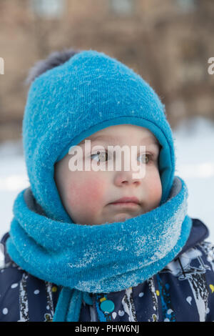 Kind Junge 2-3 Jahre im Winter draußen in blaue Schirmmütze mit pompon und Schal - snood. Close-up Portrait Stockfoto