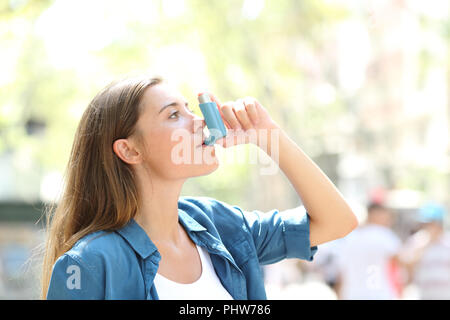 Seitenansicht portrait einer Asthmatischen Frau mit einem Inhalator draußen auf der Straße Stockfoto