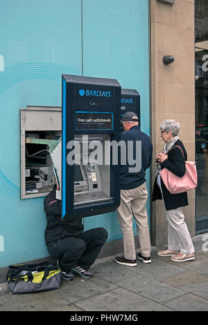 Barclays ATM gewartet, während ein reifes Paar verwenden das ATM. Stockfoto