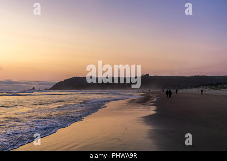 Wandern in Cannon Beach in der Dämmerung oder Sonnenuntergang mit lebhaften violetten Himmel, Küste von Oregon, USA. Stockfoto