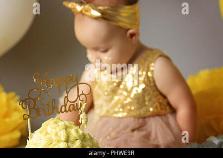 Kleines Kind ein Jahr alt Mädchen ihre yellow cake geboren zerquetscht Stockfoto