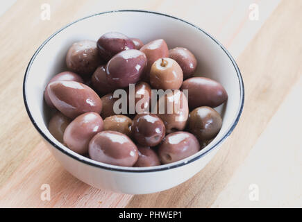 Die Oliven in einer kleinen Schüssel auf hölzernen Tisch Stockfoto