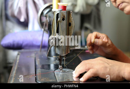 Frau Hand einfädeln Nadel in Nähmaschine Nadel Stockfoto