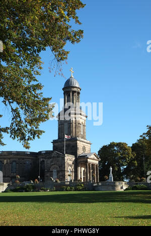 St Chad's Kirche, Shrewsbury, Shropshire, aus dem Steinbruch gesehen an einem sommerlichen Tag mit blauen Himmel. St George's Flagge außerhalb der Kirche Stockfoto