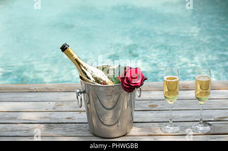 Flasche Champagner im Eiskübel und Champagner Glas durch Schwimmen p Stockfoto