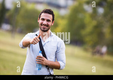 Junge Unternehmer ist Trinkwasser und Ruhen von der Arbeit im Park. Stockfoto