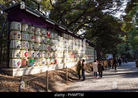 Die Menschen stehen und schauen an der Vorderseite der bunten sake Fässer in der Meiji Jingu Shrine entfernt zu einem beliebten Reiseziel Stockfoto