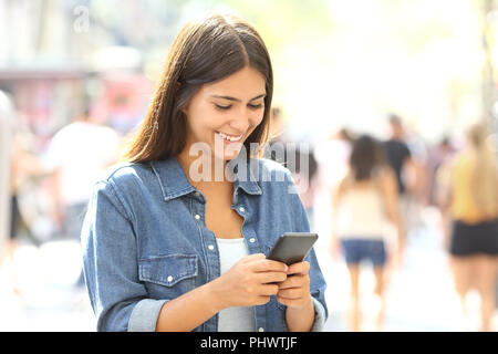 Gerne jugendlich verwendet ein smart phone auf der Straße Stockfoto