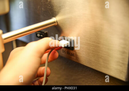 Nahaufnahme einer Hand Verbinden eines USB-Kabel in einen USB-Anschluss Stockfoto