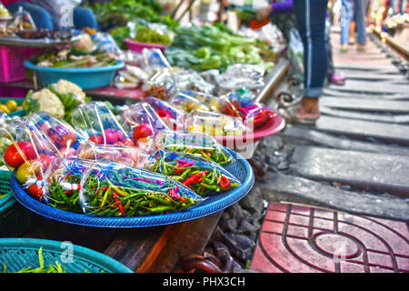 Verkauf von Speisen auf der Maeklong Railway Markt in Thailand. Stockfoto