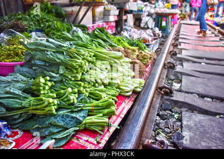 Verkauf von Speisen auf der Maeklong Railway Markt in Thailand. Stockfoto