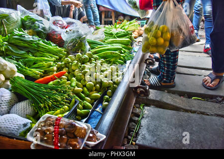 Verkauf von Speisen auf der Maeklong Railway Markt in Thailand. Stockfoto