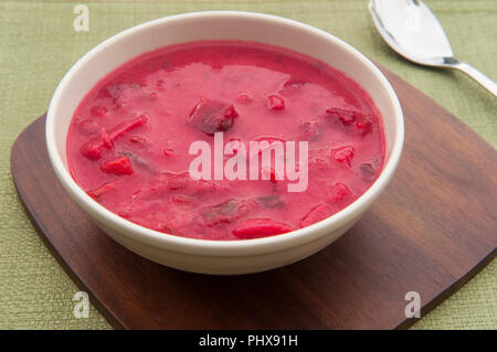 Vegetarische Zuckerrüben borscht Suppe in einer weißen Schüssel auf eine Holzplatte und grüner Hintergrund Stockfoto