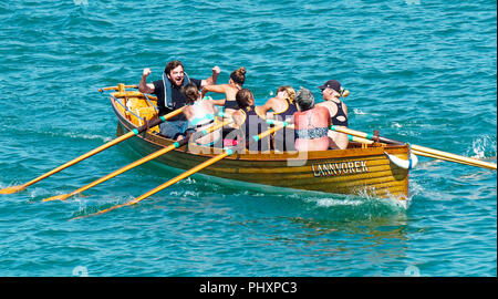 Newquay, Großbritannien. 3. September 2018. Traditionelle Pilot gig Rennen. Cornwall Damen Meisterschaft 2018, l Mounts Bay weiblichen Penzance C Crew macht durch den ausgezeichneten als Gesamtsieger im Wettbewerb. Jubilant cox Graham Nicholas begrüßt seine Veteranen klasse weibliche Mannschaft 03, September, 2018 Robert Taylor/Alamy leben Nachrichten Newquay, Cornwall, England. Credit: Robert Taylor/Alamy leben Nachrichten Stockfoto