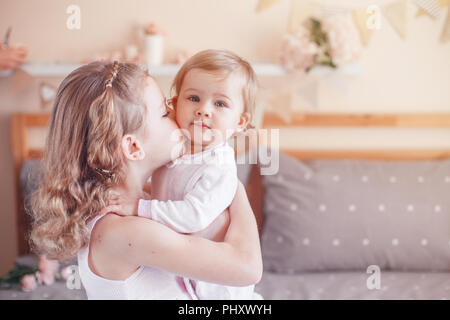 Zwei cute adorable white Kaukasischen girsl Schwestern küssen. Kinder sitzen zusammen auf dem Bett im Schlafzimmer zu spielen. Lifestyle echten Emotionen, Geschwister, lo Stockfoto