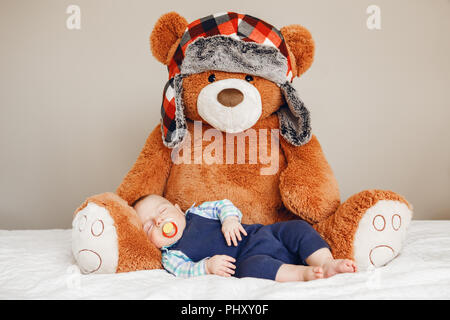 Porträt einer cute adorable White kaukasische Baby neugeborenen Jungen schlafen Träumen mit schnuller Schnuller im Mund, tragen Shirt blau Body, liegend auf dem Bett Stockfoto