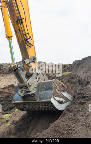 Bagger gräbt bis Boden von sandigen Hügel Stockfoto