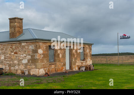 Sandstein Siedler Cottage mit damit wir Flagge weht im Wind vergessen. Stockfoto