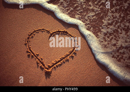 Herz auf dem Sand des Strandes gezeichnet. Stockfoto
