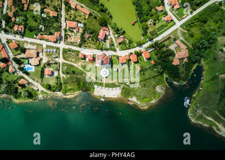 Luftbild des kleinen Dorfes auf einem See Küste mit ruhigem Wasser. Stockfoto