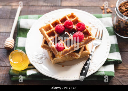 Belgische Waffeln mit Himbeeren und Honig. Platz mit hausgemachten belgischen Waffeln. Leckeres Frühstück. Stockfoto