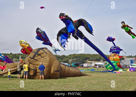 Lemwerder, Deutschland - 18 August, 2018 - eine große braune Drachen in der Form eines Dinosauriers wird am Lemwerder Drachenfest vorbereitet, während andere Stockfoto