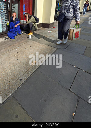 Frau im Gespräch mit einem Obdachlosen auf der Straße. London, England, UK. Stockfoto