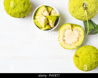 Grüne Frucht maclura pomifera, osage Orange, Apple, Adam apple wachsen auf weiße Holztisch. Maclura Stücke der Platte bereit für Salbe Vorbereitung. Kopieren Sie Platz. Top View oder flach. Stockfoto