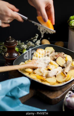 Gebratene Kartoffeln in einer Pfanne mit Kletterpflanzen und Gewürzen. Leckere hausgemachte Mittagessen. Grauer Hintergrund und Platz für Text. Ansicht von oben. Stockfoto