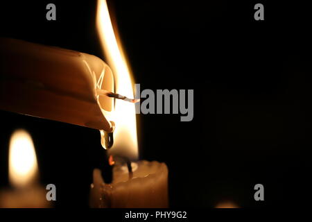 Eine Kerze in der Dunkelheit, Tropfen geschmolzenen Wachs, Flamme. Close Up. Weihnachten, Neujahr Grußkarte, Hintergrund, Kirche, Religion, Glaube, Gebet, Urlaub, winter fairy tale, Halloween. Stockfoto