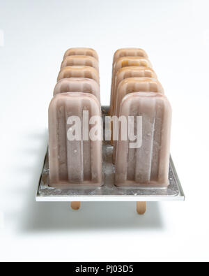 Schokoladeneis auf Stick in Kunststoffformen mit glänzenden Schatten auf weißem Hintergrund mit Platz für Text. Stockfoto