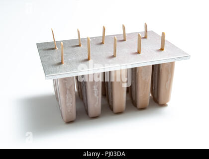 Hausgemachte Bio Schokolade Eis lolly in Kunststoffformen mit einer Reflexion der Schatten auf weißem Hintergrund mit kopieren. Stockfoto