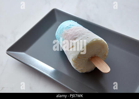 Close-up in einer schwarzen Platte eine Frucht farbige Eis auf einem Stock auf grauem Marmor Tisch mit Platz für Text. Flach Stockfoto