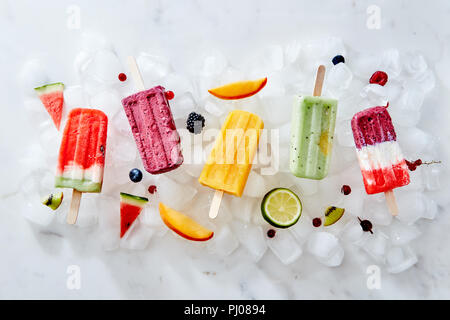 Verschiedene Eis auf einem Stick und verschiedene Stücke von Obst und Beeren auf Eiswürfel. Flach Stockfoto