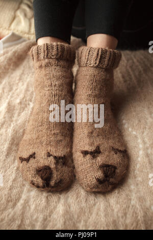 Gemütliche Winter Herbst Herbst Lifestyle: Frau feets Beine in warmen süssen Bär Socken. Retro, Tonisierung, beige Monochrom, hipster Still Life Stockfoto