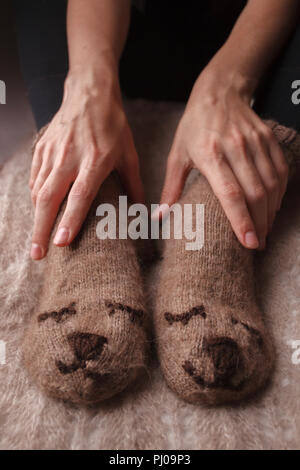 Gemütliche Winter Herbst Herbst Lifestyle: Frau feets Beine in warmen süssen Bär Socken. Retro, Tonisierung, beige Monochrom, hipster Still Life Stockfoto