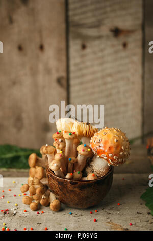 Holz, Märchen & mysteriösen Wesen, das Konzept - poisonus Pilze in den Kelch mit Süßwaren Dekor auf Holztisch, Magie, fantastisches Essen Stockfoto