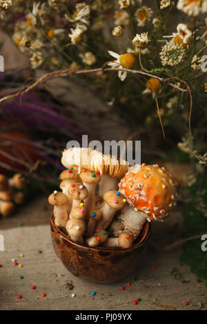 Holz, Märchen & mysteriösen Wesen, das Konzept - poisonus Pilze in den Kelch mit Süßwaren Dekor auf Holztisch, Magie, fantastisches Essen Stockfoto