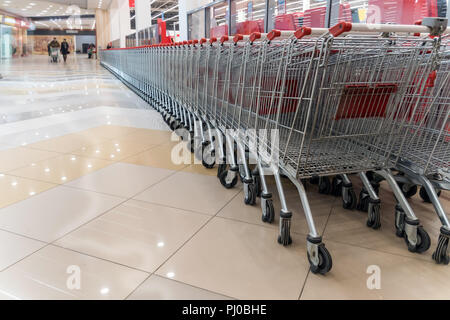 Reihe von leeren Einkaufswagen im Supermarkt extrem flache Tiefenschärfe, Schwerpunkt auf das vierte Rad von rechts Stockfoto