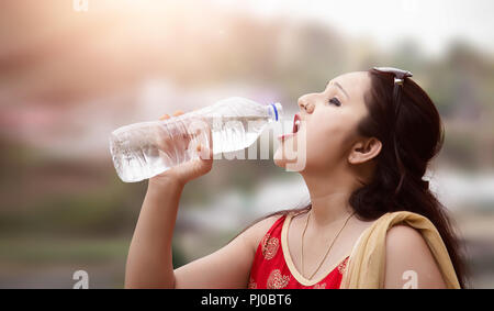 Schönen indischen Frau trinkt Wasser aus der Flasche Stockfoto