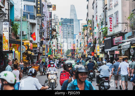 Ho Chi Minh, Vietnam: Bui Vien Straße mit zahlreichen Hotel, Bar und Shop Schilder, mit Menschen & Bikes mit Blick auf bitexco Financial Tower überfüllt. Stockfoto